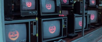 Movie still from “Halloween III: Season of the Witch” (1982), directed by Tommy Lee Wallace – A tv with a picture of a pumpkin on it; Medium shot, High angle