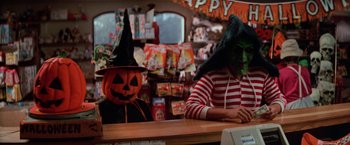 Movie still from “Halloween III: Season of the Witch” (1982), directed by Tommy Lee Wallace – Two people sitting at a counter wearing halloween costumes; Medium shot, Over the shoulder angle
