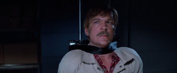 Movie still from “Halloween III: Season of the Witch” (1982), directed by Tommy Lee Wallace – A man wearing a neck brace and a plaid shirt; Close Up shot, Low angle