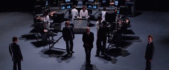 Movie still from “Halloween III: Season of the Witch” (1982), directed by Tommy Lee Wallace – A group of men standing in front of monitors; Wide shot, High angle