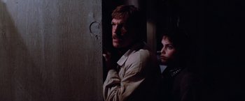 Movie still from “Halloween III: Season of the Witch” (1982), directed by Tommy Lee Wallace – A man and a woman standing next to each other in a room; Close Up shot, Over the shoulder angle