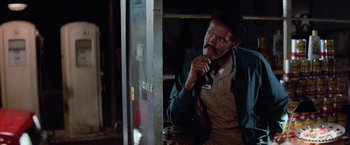 Movie still from “Halloween III: Season of the Witch” (1982), directed by Tommy Lee Wallace – A man sitting in front of a door looking at something; Medium shot, Low angle