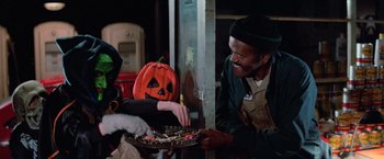 Movie still from “Halloween III: Season of the Witch” (1982), directed by Tommy Lee Wallace – A man and a woman sitting at a table with a tray of candy; Medium shot, Over the shoulder angle