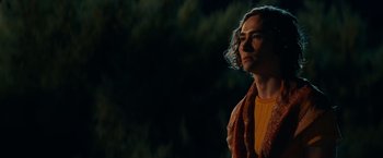 Movie still from “Halloween Kills” (2021), directed by David Gordon Green – A man with long brown hair wearing a yellow shirt and a brown scarf; Medium shot, Low angle