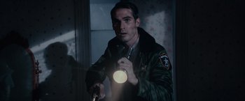 Movie still from “Halloween Kills” (2021), directed by David Gordon Green – A man holding a flashlight while wearing a uniform; Medium shot, Over the shoulder angle