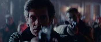 Movie still from “Halloween Kills” (2021), directed by David Gordon Green – A man holding a gun while standing next to another man; Close Up shot, Over the shoulder angle