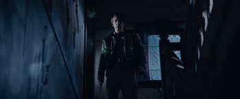 Movie still from “Halloween Kills” (2021), directed by David Gordon Green – A man holding a gun while standing next to a window; Medium shot, Low angle