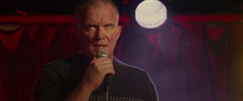 Movie still from “Halloween Kills” (2021), directed by David Gordon Green – A man is holding a microphone in front of a light; Close Up shot, Over the shoulder angle