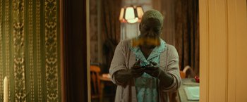Movie still from “Halloween Kills” (2021), directed by David Gordon Green – An older woman holding a cell phone in front of a mirror; Medium shot, Low angle