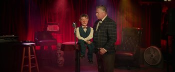 Movie still from “Halloween Kills” (2021), directed by David Gordon Green – A man standing next to a microphone with a man sitting on it; Wide shot, Over the shoulder angle