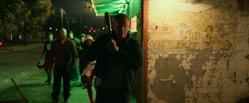 Movie still from “Halloween Kills” (2021), directed by David Gordon Green – A man holding a baseball bat while standing next to a building; Medium shot, Low angle
