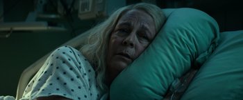 Movie still from “Halloween Kills” (2021), directed by David Gordon Green – An older woman laying in a bed with a pillow; Close Up shot, High angle