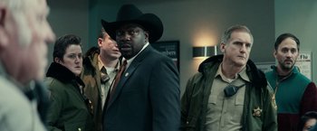 Movie still from “Halloween Kills” (2021), directed by David Gordon Green – A man wearing a cowboy hat standing next to two other men; Medium shot, Over the shoulder angle