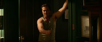 Movie still from “Halloween Kills” (2021), directed by David Gordon Green – A man in a white tank top holding a wooden stick; Medium shot, Low angle