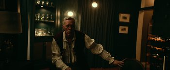 Movie still from “Halloween Kills” (2021), directed by David Gordon Green – A man wearing a vest sitting in a room; Medium shot, Over the shoulder angle