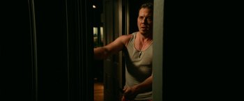 Movie still from “Halloween Kills” (2021), directed by David Gordon Green – A man holding a pair of scissors in a room; Medium shot, Over the shoulder angle