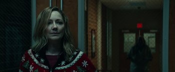 Movie still from “Halloween Kills” (2021), directed by David Gordon Green – A woman wearing a christmas sweater standing in front of a window; Medium shot, Over the shoulder angle