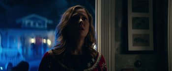 Movie still from “Halloween Kills” (2021), directed by David Gordon Green – A woman in a red and white sweater looking out of a window; Close Up shot, Over the shoulder angle