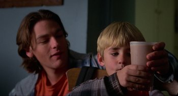 Movie still from “Halloween: The Curse of Michael Myers” (1995), directed by Joe Chappelle – A young man and a young boy looking at a cell phone; Close Up shot, Over the shoulder angle