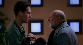 Movie still from “Halloween: The Curse of Michael Myers” (1995), directed by Joe Chappelle – A man and a man holding a baby in a room; Close Up shot, Over the shoulder angle