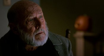 Movie still from “Halloween: The Curse of Michael Myers” (1995), directed by Joe Chappelle – An old man with a beard is sitting in a chair; Close Up shot, Over the shoulder angle