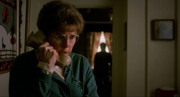 Movie still from “Halloween: The Curse of Michael Myers” (1995), directed by Joe Chappelle – An older woman talking on a phone in front of a window; Close Up shot, Over the shoulder angle