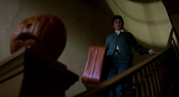 Movie still from “Halloween: The Curse of Michael Myers” (1995), directed by Joe Chappelle – A woman standing on a flight of stairs holding a suitcase; Wide shot, Low angle