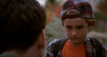 Movie still from “Halloween: The Curse of Michael Myers” (1995), directed by Joe Chappelle – A young boy wearing a plaid hat and a backpack; Close Up shot, Over the shoulder angle