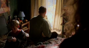 Movie still from “Halloween: The Curse of Michael Myers” (1995), directed by Joe Chappelle – A man sitting on a bed looking out a window; Medium shot, Over the shoulder angle