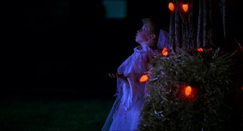 Movie still from “Halloween: The Curse of Michael Myers” (1995), directed by Joe Chappelle – A young child dressed as a ghost standing next to a christmas tree; Medium shot, Low angle