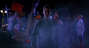 Movie still from “Halloween: The Curse of Michael Myers” (1995), directed by Joe Chappelle – A man standing in the dark with balloons in the background; Medium shot, Low angle