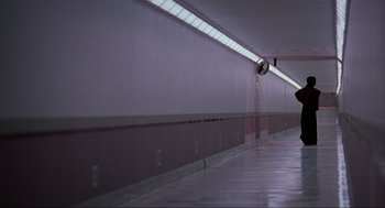 Movie still from “Halloween: The Curse of Michael Myers” (1995), directed by Joe Chappelle – A person walking down a hallway with a light on the side of the wall; Extreme Wide shot, Low angle