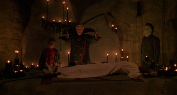 Movie still from “Halloween: The Curse of Michael Myers” (1995), directed by Joe Chappelle – A man standing next to a bed with candles on it; Wide shot, Low angle