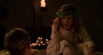 Movie still from “Halloween: The Curse of Michael Myers” (1995), directed by Joe Chappelle – A woman wearing a crown sitting in front of a fireplace; Medium shot, Over the shoulder angle