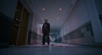 Movie still from “Halloween: The Curse of Michael Myers” (1995), directed by Joe Chappelle – A man in a mask standing in a hallway; Wide shot, Low angle