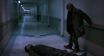 Movie still from “Halloween: The Curse of Michael Myers” (1995), directed by Joe Chappelle – A man standing next to a dead body in a hallway; Wide shot, Low angle