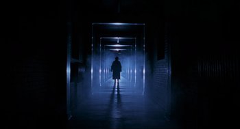 A person is standing in a dark hallway