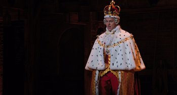 Movie still from “Hamilton” (2020), directed by Thomas Kail – A man wearing a crown and a cape; Medium shot, Low angle