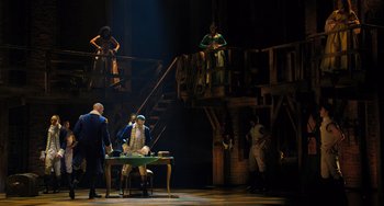 Movie still from “Hamilton” (2020), directed by Thomas Kail – A group of people standing around a table; Wide shot, Over the shoulder angle