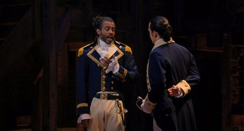 Movie still from “Hamilton” (2020), directed by Thomas Kail – A man in a blue and yellow uniform talking to another man in a blue and yellow uniform; Medium shot, Over the shoulder angle