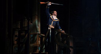 Movie still from “Hamilton” (2020), directed by Thomas Kail – A man in a blue and yellow uniform holding a sword; Wide shot, Low angle