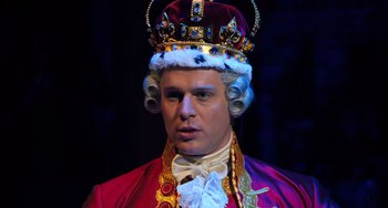 Movie still from “Hamilton” (2020), directed by Thomas Kail – A man wearing a red robe and a crown; Close Up shot, High angle