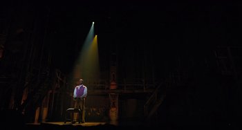 Movie still from “Hamilton” (2020), directed by Thomas Kail – A man standing on a stage under a spotlight; Extreme Wide shot, Low angle
