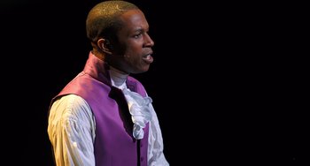 Movie still from “Hamilton” (2020), directed by Thomas Kail – A man wearing a purple vest and white shirt; Close Up shot, High angle