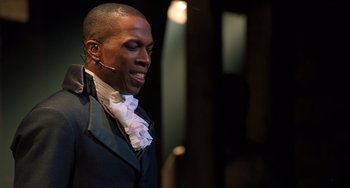 Movie still from “Hamilton” (2020), directed by Thomas Kail – A man in a black suit and a white neck tie; Close Up shot, Over the shoulder angle