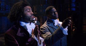 Movie still from “Hamilton” (2020), directed by Thomas Kail – A couple of men standing next to each other; Medium shot, Low angle