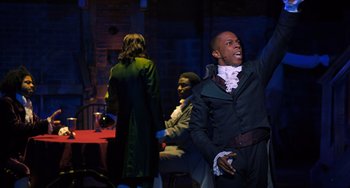 Movie still from “Hamilton” (2020), directed by Thomas Kail – A group of people sitting at a table; Medium shot, Over the shoulder angle