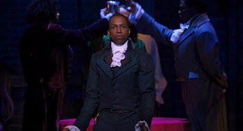 Movie still from “Hamilton” (2020), directed by Thomas Kail – A man standing in front of a group of people; Medium shot, Over the shoulder angle