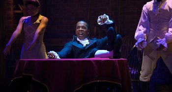 Movie still from “Hamilton” (2020), directed by Thomas Kail – A man sitting at a table in a dark room; Medium shot, High angle