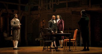 Movie still from “Hamilton” (2020), directed by Thomas Kail – A couple of men standing next to each other on top of a table; Wide shot, Over the shoulder angle